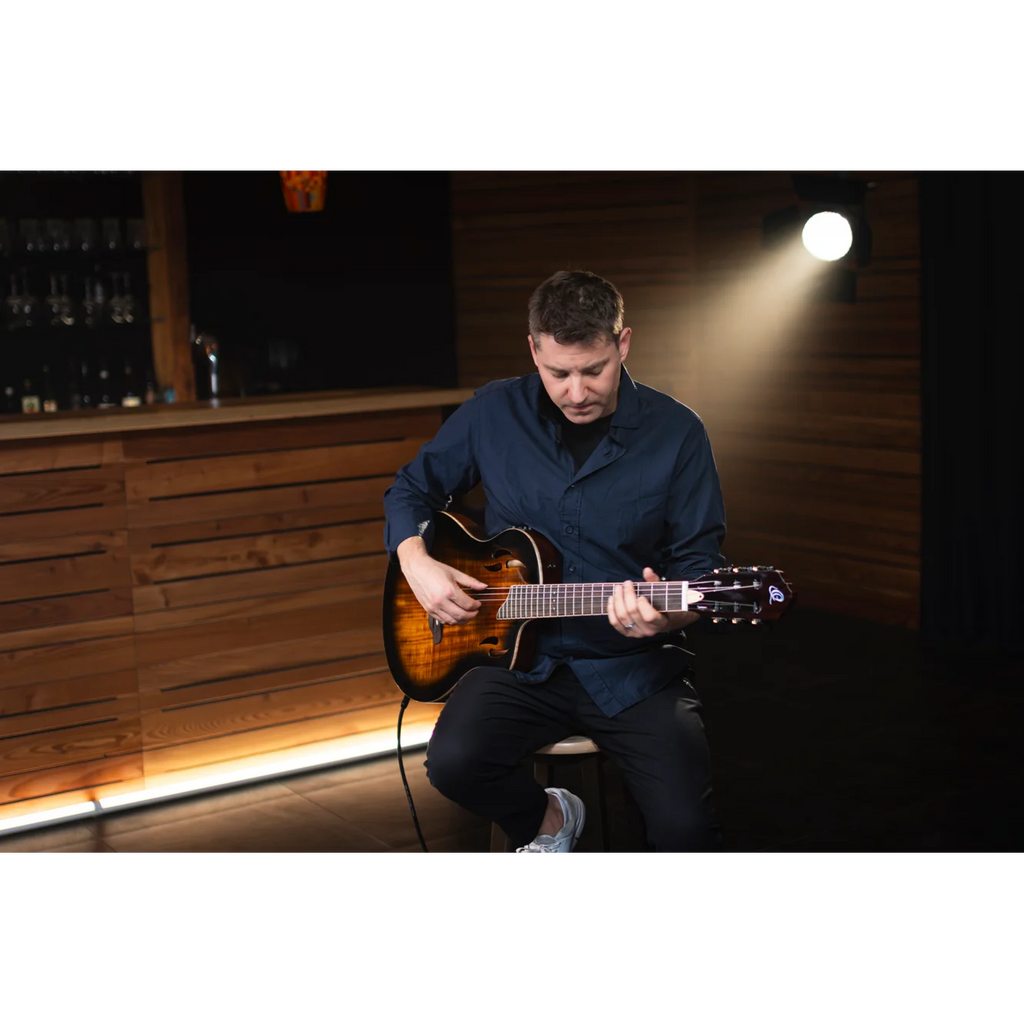 Man playing electric nylon string guitar in a dimly lit room with wooden walls in sydney, australia.