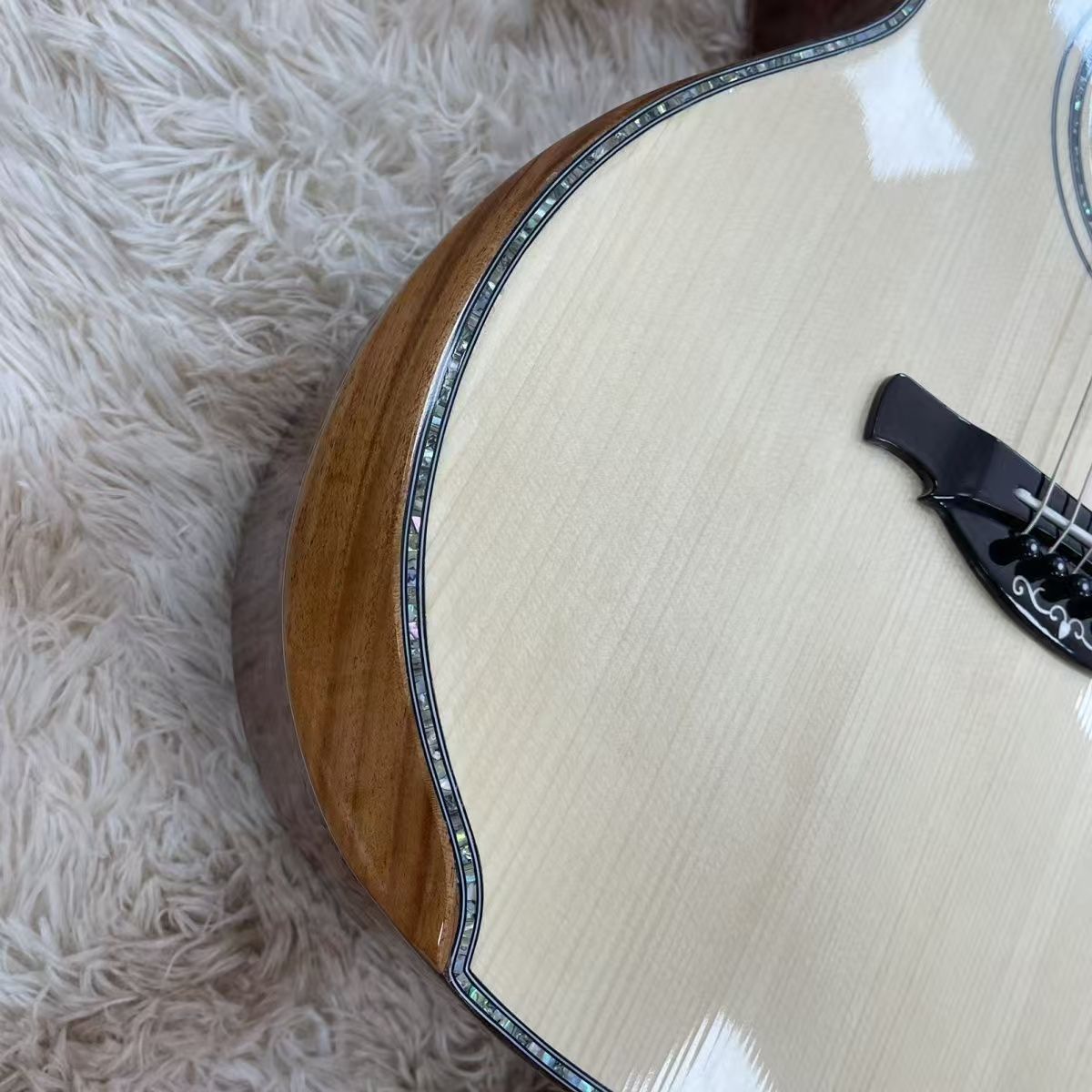 Close-up view of a guitar from the side  on a textured surface, probably a rug