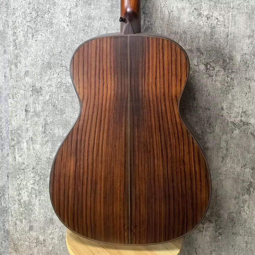 Wooden acoustic guitar back shown on a textured gray marble background