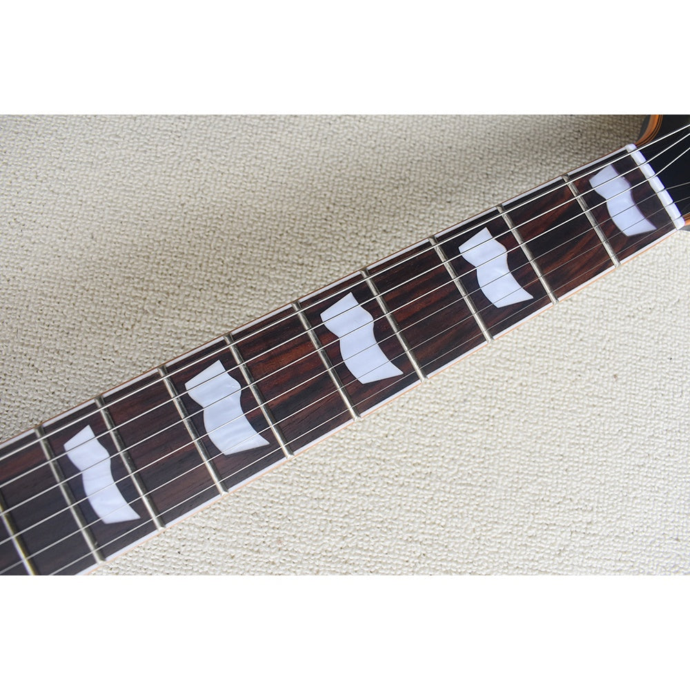 Close-up of a guitar neck with white inlay dots on a beige surface