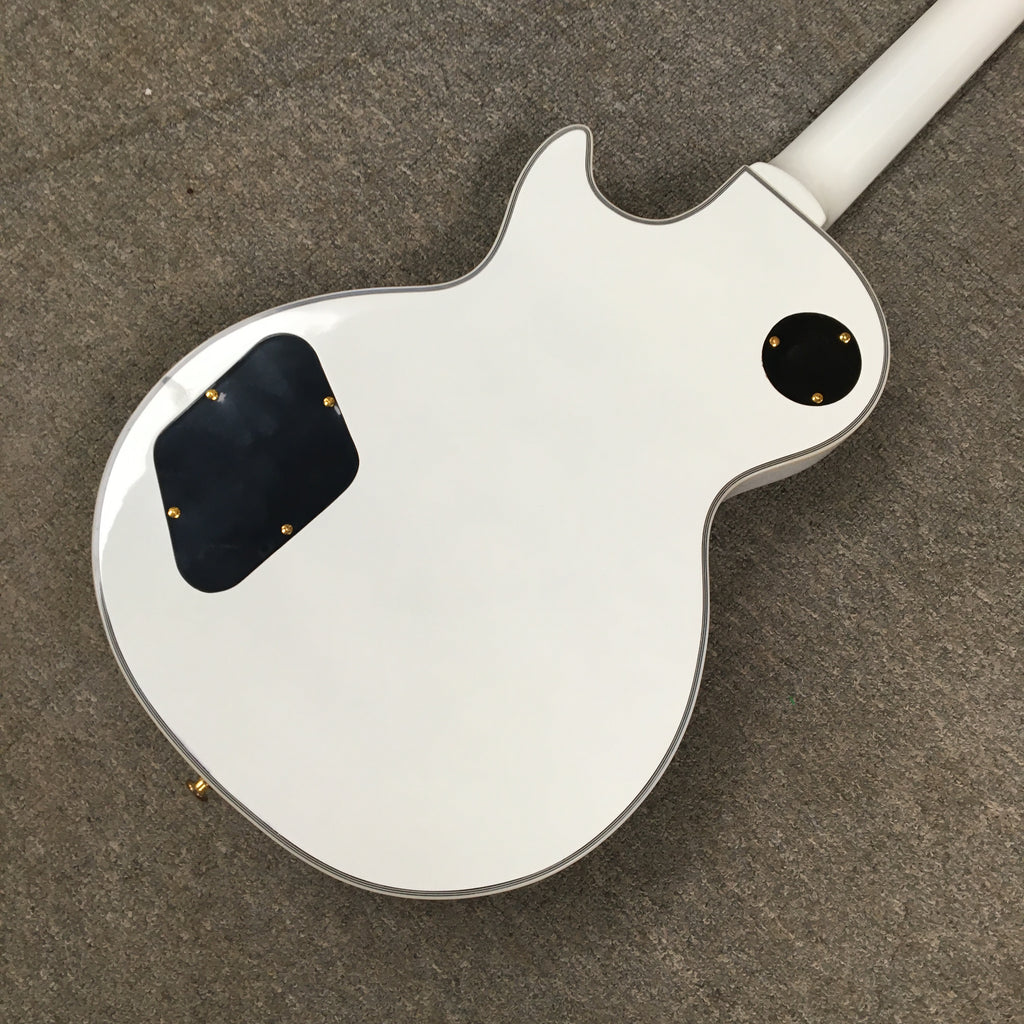back side view of a White electric guitar on a brown surface, looks like it was placed on a carpet.