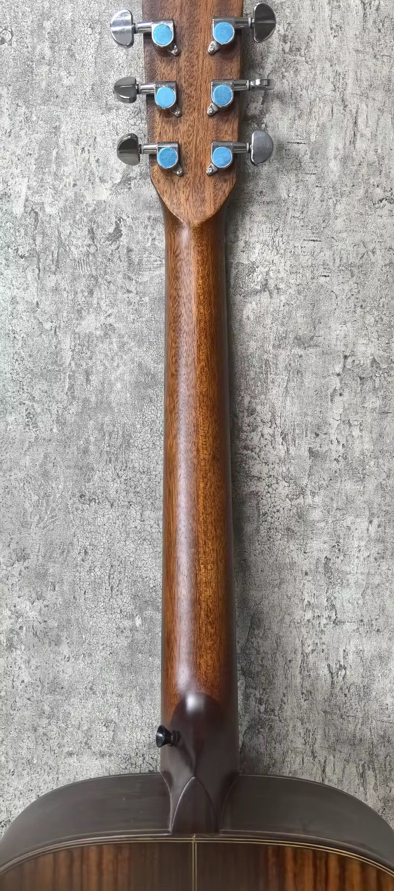Close-up of a mandolin's headstock and neck against a textured gray background