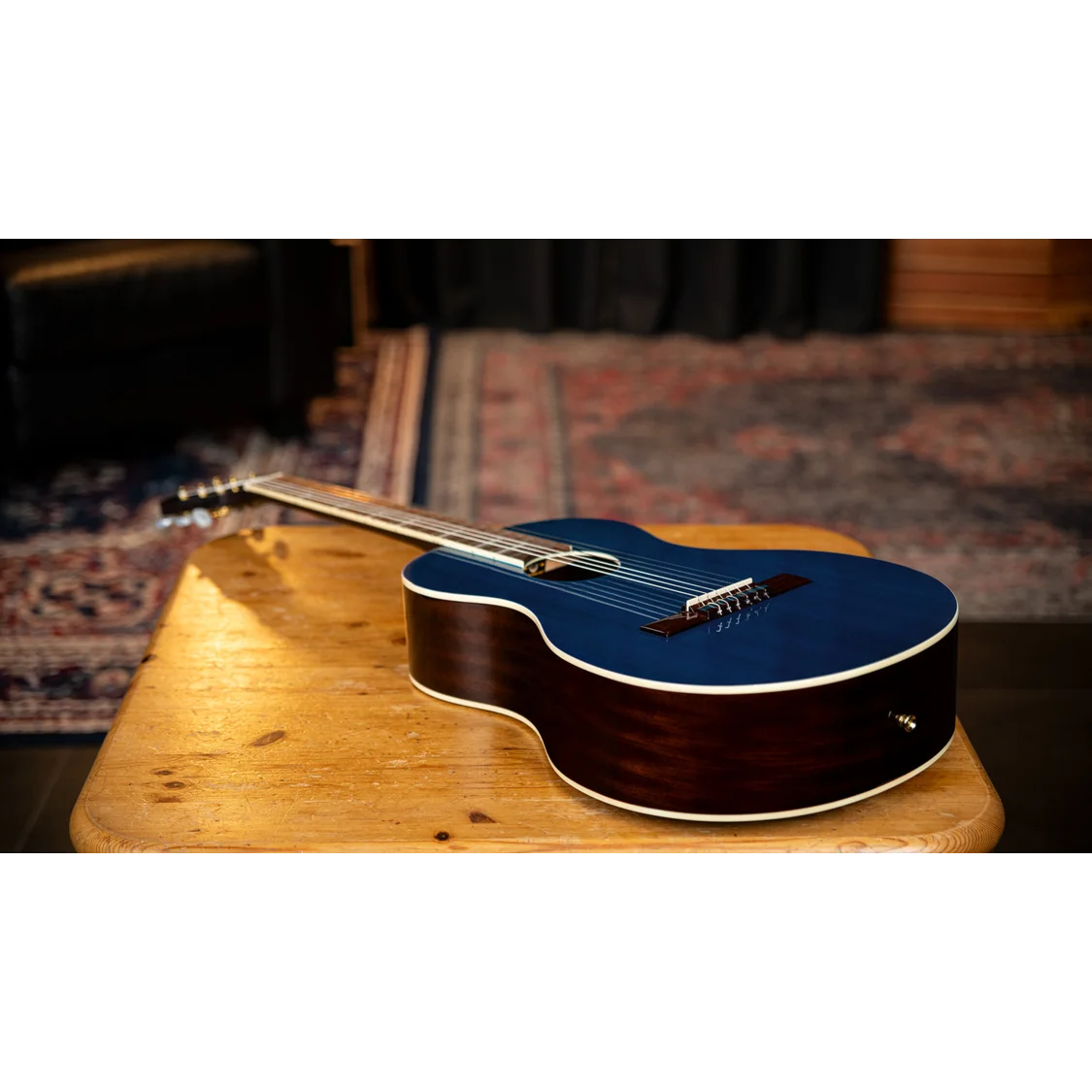 Blue acoustic guitar on a wooden table with a blurred background