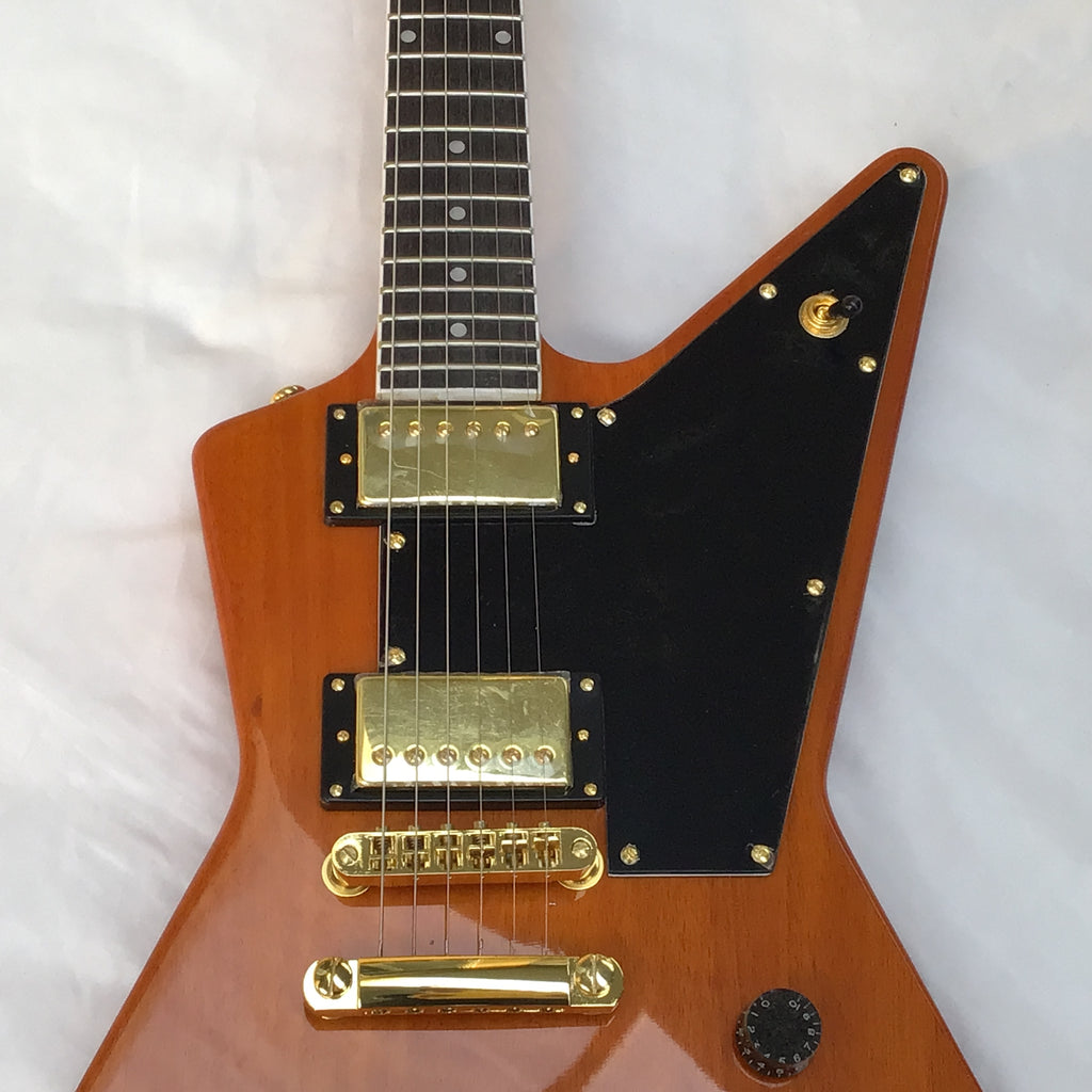 Electric guitar with a wooden body and gold hardware on a white background