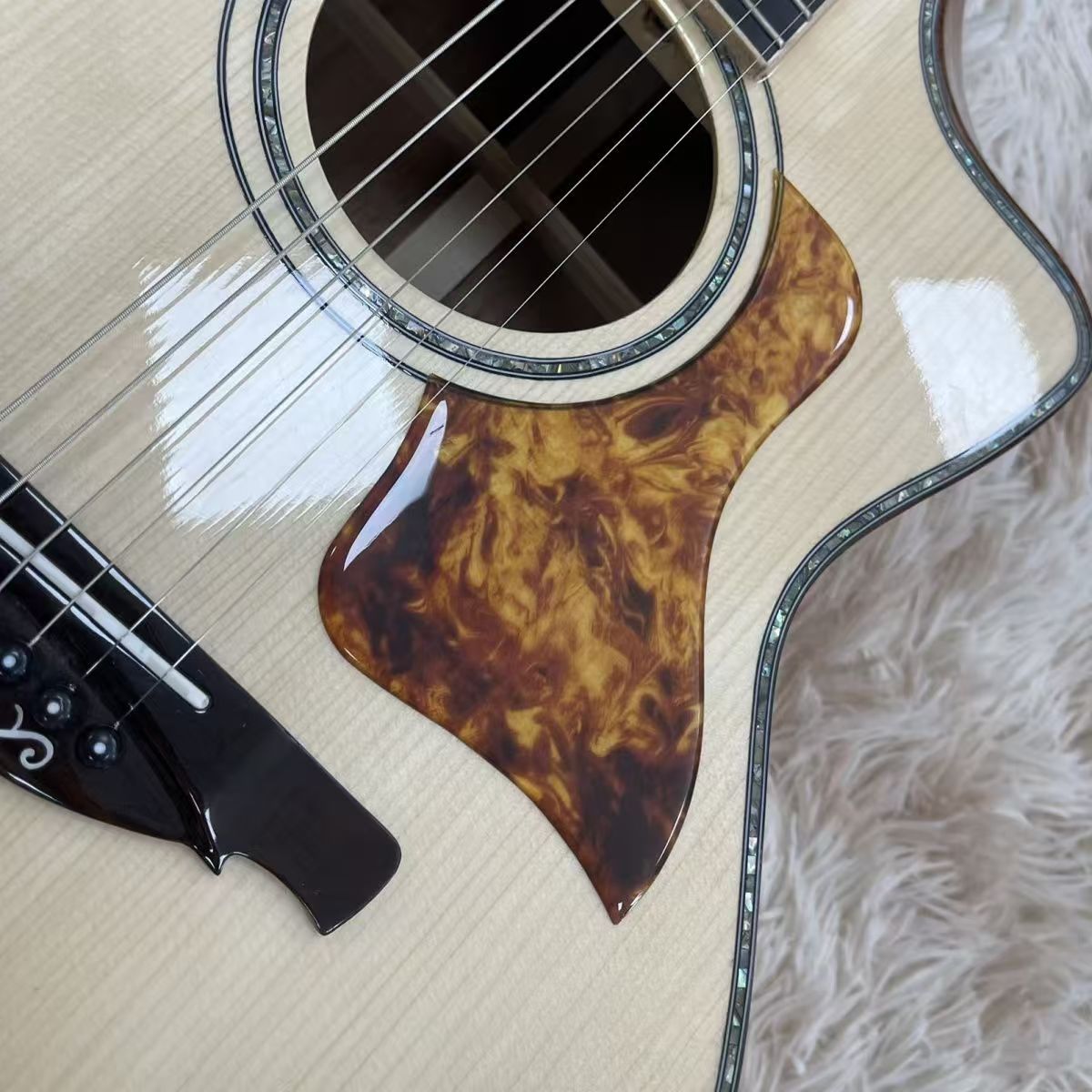 High gloss spruce top acoustic guitar bridge and pickguard close-up