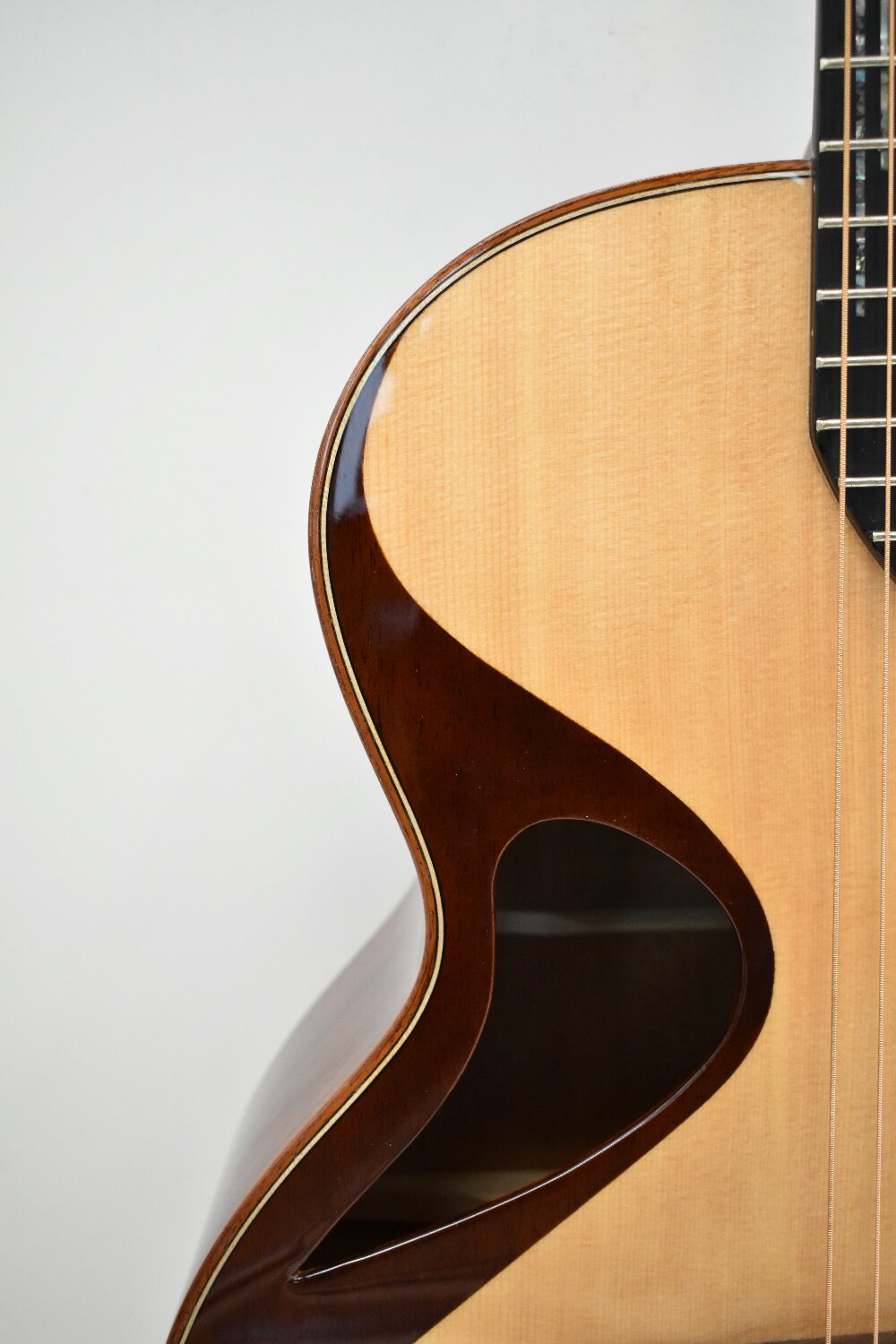 Side view of spruce top acoustic guitar with sculpted body design