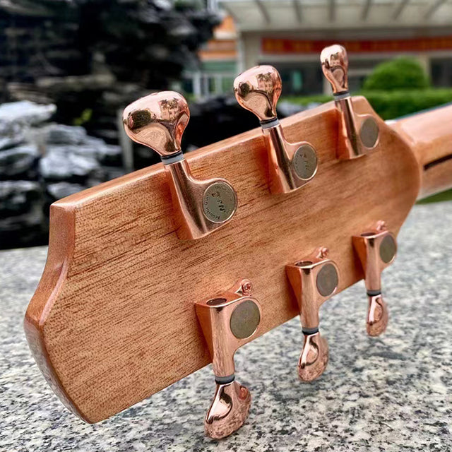 Wooden guitar neck with copper tuning pegs on a stone surface